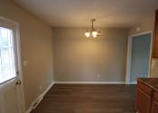 Thumbnail 31 of 39 - A room with a brown floor and a chandelier hanging from the ceiling.