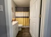 Thumbnail 10 of 27 - a bathroom with a toilet and a yellow and white shower curtain