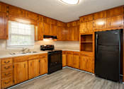 Thumbnail 2 of 30 - A kitchen with wooden cabinets and a black refrigerator.
