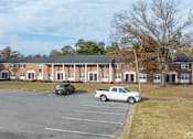 Thumbnail 4 of 30 - A white truck is parked in a parking lot in front of a building.