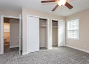 Thumbnail 21 of 30 - A room with a ceiling fan and carpeted floor.
