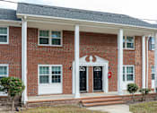 Thumbnail 20 of 30 - A red brick house with white columns and a black door.