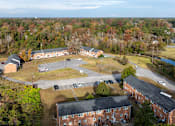 Thumbnail 1 of 30 - An aerial view of a parking lot and buildings with trees in the background.