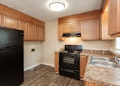 Thumbnail 5 of 30 - A kitchen with black appliances and wooden cabinets.