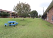 Thumbnail 24 of 29 - a large yard in front of a building with a blue picnic table