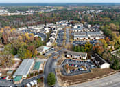 Thumbnail 23 of 25 - An aerial view of a parking lot and buildings with trees in the background.