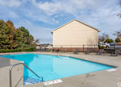 Thumbnail 5 of 25 - A swimming pool with a diving board and a building in the background.