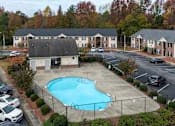 Thumbnail 14 of 25 - A swimming pool is surrounded by a fence and a building.