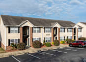 Thumbnail 18 of 25 - A red car is parked in the parking lot of a building with the number 2550 on it.