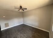 Thumbnail 22 of 27 - an empty living room with a ceiling fan and wood floors