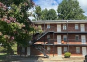 Thumbnail 19 of 27 - a red brick apartment building with stairs and trees