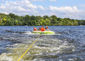 Thumbnail 22 of 25 - Four people are riding a banana boat on a lake.at Residence at Marina Bay, South Carolina
