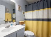 Thumbnail 5 of 27 - a bathroom with a yellow shower curtain and a white sink and toilet