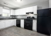 Thumbnail 18 of 27 - an empty kitchen with black appliances and white cabinets