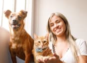 Thumbnail 22 of 29 - a woman sitting on a couch with a dog and a cat
