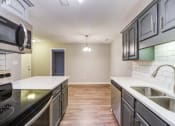Thumbnail 25 of 27 - an empty kitchen with stainless steel appliances and white counter tops