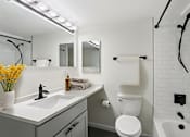 Thumbnail 3 of 22 - A white toilet is in a bathroom with a white sink and a white tub.