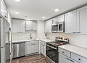 Thumbnail 2 of 22 - A modern kitchen with white cabinets and stainless steel appliances.