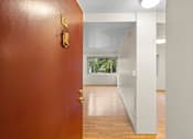 Thumbnail 19 of 50 - an empty room with a red door and a hallway to a white room
