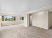 Thumbnail 25 of 50 - a living room with white walls and a large window