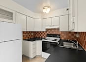 Thumbnail 21 of 50 - a kitchen with black counter tops and white appliances