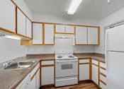 Thumbnail 42 of 50 - an empty kitchen with white appliances and wooden cabinets at Summer Creek Apartments, Tigard