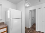 Thumbnail 30 of 50 - a white kitchen with a refrigerator and a door to a hallway at Summer Creek Apartments, Tigard, 97223