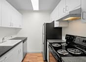 Thumbnail 33 of 47 - a kitchen with white cabinets and a black stove and refrigerator