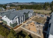 Thumbnail 26 of 27 - an aerial view of an apartment building with green and white buildings and a parking lot at Sonder Fields in Happy Valley, OR