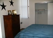 Thumbnail 16 of 17 - A bedroom with a blue bedspread and a wooden dresser.