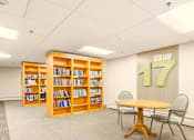 Thumbnail 1 of 18 - A room with a table, chairs and a bookshelf with the number 17 on the wall.