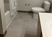 Thumbnail 115 of 115 - A white toilet sits in a bathroom next to a white sink.