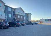 Thumbnail 98 of 115 - A parking lot with several cars and apartment buildings in the background.