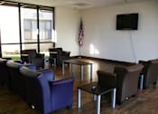 Thumbnail 9 of 17 - A room with purple chairs and a flat screen TV mounted on the wall.