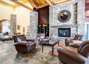 Thumbnail 20 of 30 - a living room with leather furniture and a stone fireplace at Madison Sierra Sun, Puyallup, WA