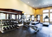 Thumbnail 25 of 30 - a gym with weights and cardio equipment and windows at Madison Sierra Sun, Puyallup, Washington