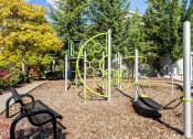 Thumbnail 26 of 30 - a childrens play area in a park with a bench at Madison Sierra Sun, Puyallup, WA
