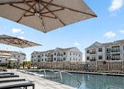 Thumbnail 44 of 124 - A pool area with sun umbrellas and apartment buildings in the background at Madison Prickett Preserve, Yardley Pennsylvania