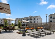 Thumbnail 48 of 124 - A patio with chairs and umbrellas in front of apartment buildings at Madison Prickett Preserve, Yardley