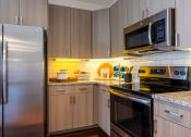 Thumbnail 13 of 33 - a kitchen with stainless steel appliances and wooden cabinets at The Parkway on Westlake, Texas, 77346