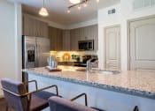 Thumbnail 11 of 33 - a kitchen with a counter top and a stainless steel refrigerator at The Parkway on Westlake, Humble, Texas