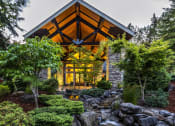 Thumbnail 1 of 30 - a home in the woods with a stone and wood exterior at Madison Sierra Sun, Puyallup, 98374