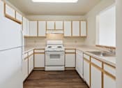 Thumbnail 4 of 26 - A kitchen with white appliances and wooden cabinets.