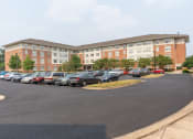 Thumbnail 2 of 17 - a large brick building with a parking lot in front of it