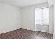 Thumbnail 8 of 16 - Empty room with wooden flooring and a window.