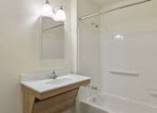 Thumbnail 26 of 26 - A white bathroom with a sink, mirror, and bathtub.