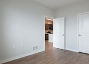 Thumbnail 9 of 18 - A room with two doors and a hallway leading to another room.