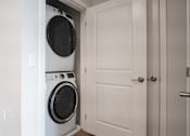 Thumbnail 11 of 18 - A white washing machine is in a white doorway.