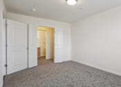 Thumbnail 14 of 30 - A room with white walls and carpeted floor with two doors open.