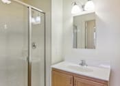 Thumbnail 18 of 30 - A bathroom with a sink, mirror, and shower.